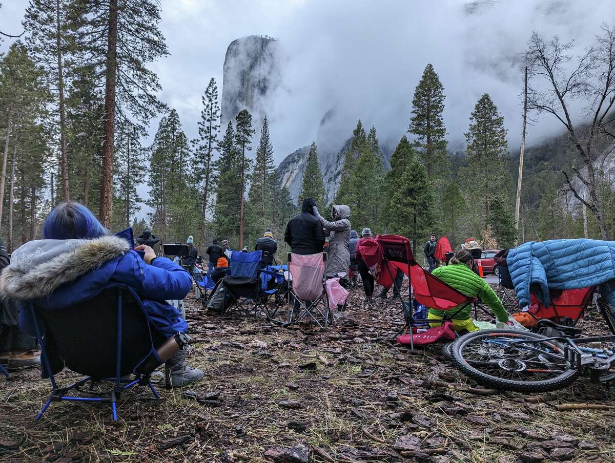 Firefall hopefuls watch as clouds obscure Horsetail Falls on Yosemite's El Capitan on Feb. 11, 2023.