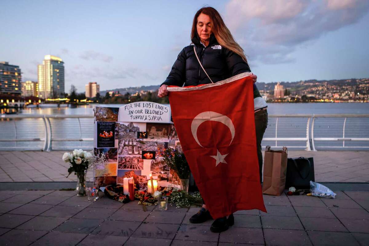 At a vigil Tuesday in Oakland, Cigdem Cogur, from Adana, Turkey, speaks to dozens while holding the flag of Turkey while honoring the thousands of lives lost and injured in an earthquake that shook Turkey and Syria. Cogur said she has had trouble reaching her family since the quake.