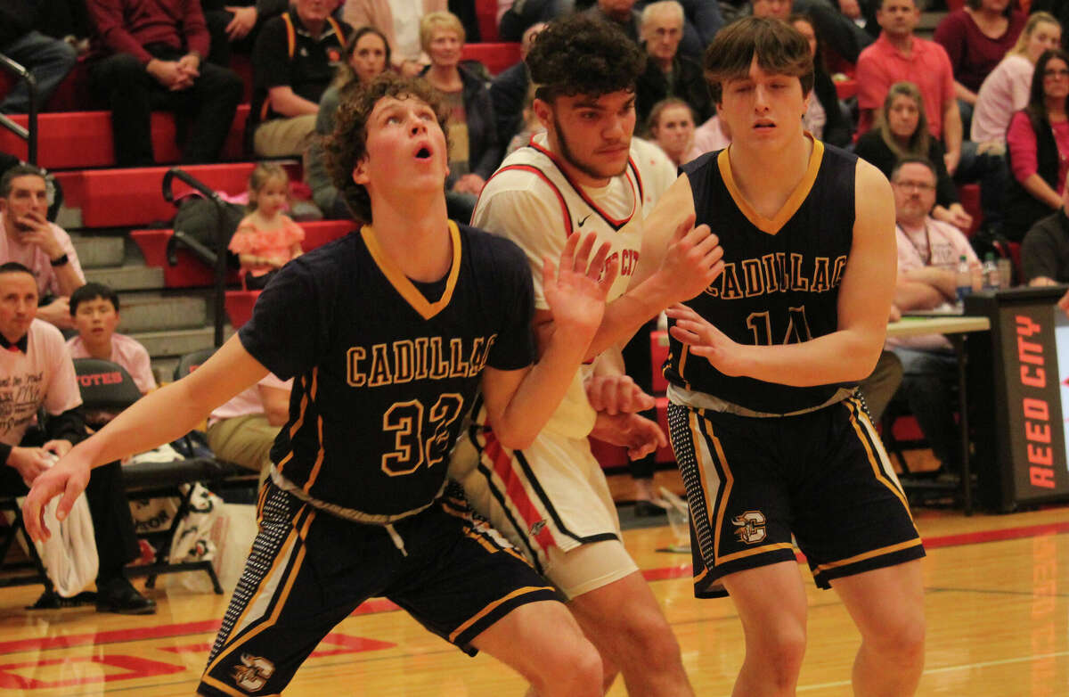 Reed City's Xavier Allen (middle) battles for rebound positioning on a free throw attempt with Cadillac's  Charlie Howell (32) and Grant Williams (14).