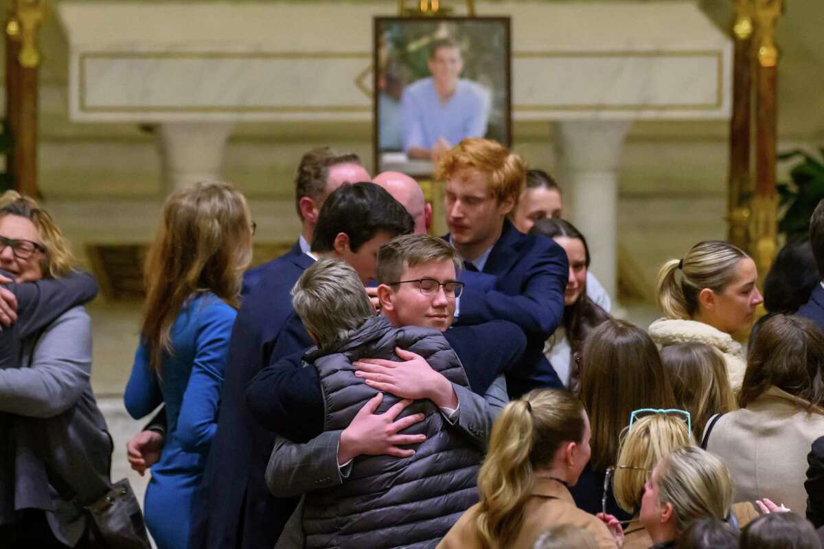 Friends and supporters console each other during a memorial service for Brian Fraser at St. Paul on the Lake Catholic Church in Grosse Pointe Farms, Mich., on Tuesday, Feb. 14, 2023. Fraser was identified as one of the students slain during a mass shooting on Michigan State University's campus the night before. (David Guralnick/Detroit News via AP, Pool)