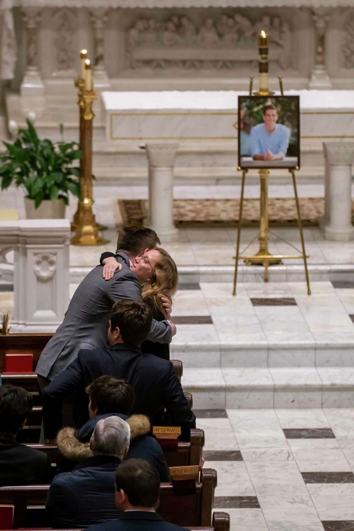 Friends and supporters console each other during a memorial service for Brian Fraser at St. Paul on the Lake Catholic Church in Grosse Pointe Farms, Mich., on Tuesday, Feb. 14, 2023. Fraser was identified as one of three students slain during a mass shooting on Michigan State University's campus the night before. (David Guralnick/Detroit News via AP, Pool)