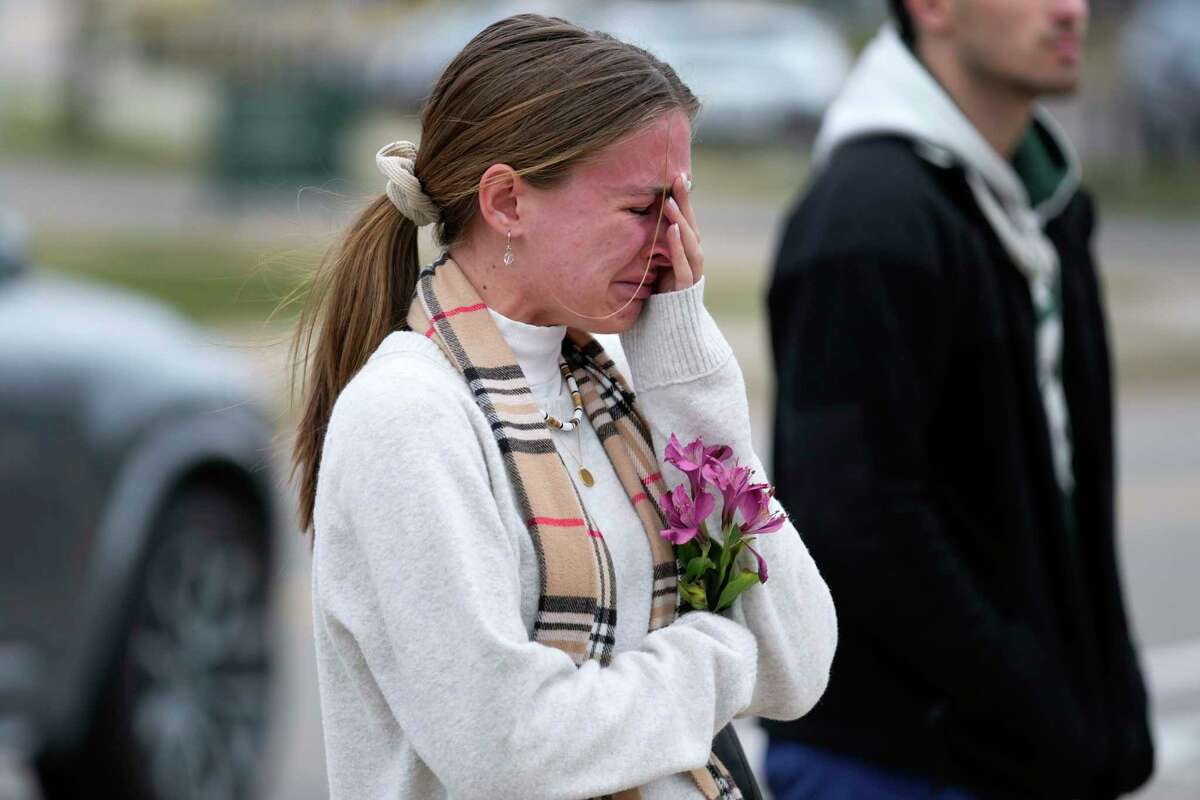 A student cries where flowers are being left at the Spartan Statue on the grounds of Michigan State University, in East Lansing, Mich., Tuesday, Feb. 14, 2023. A gunman killed several people and wounded others at Michigan State University. Police said early Tuesday that the shooter eventually killed himself.