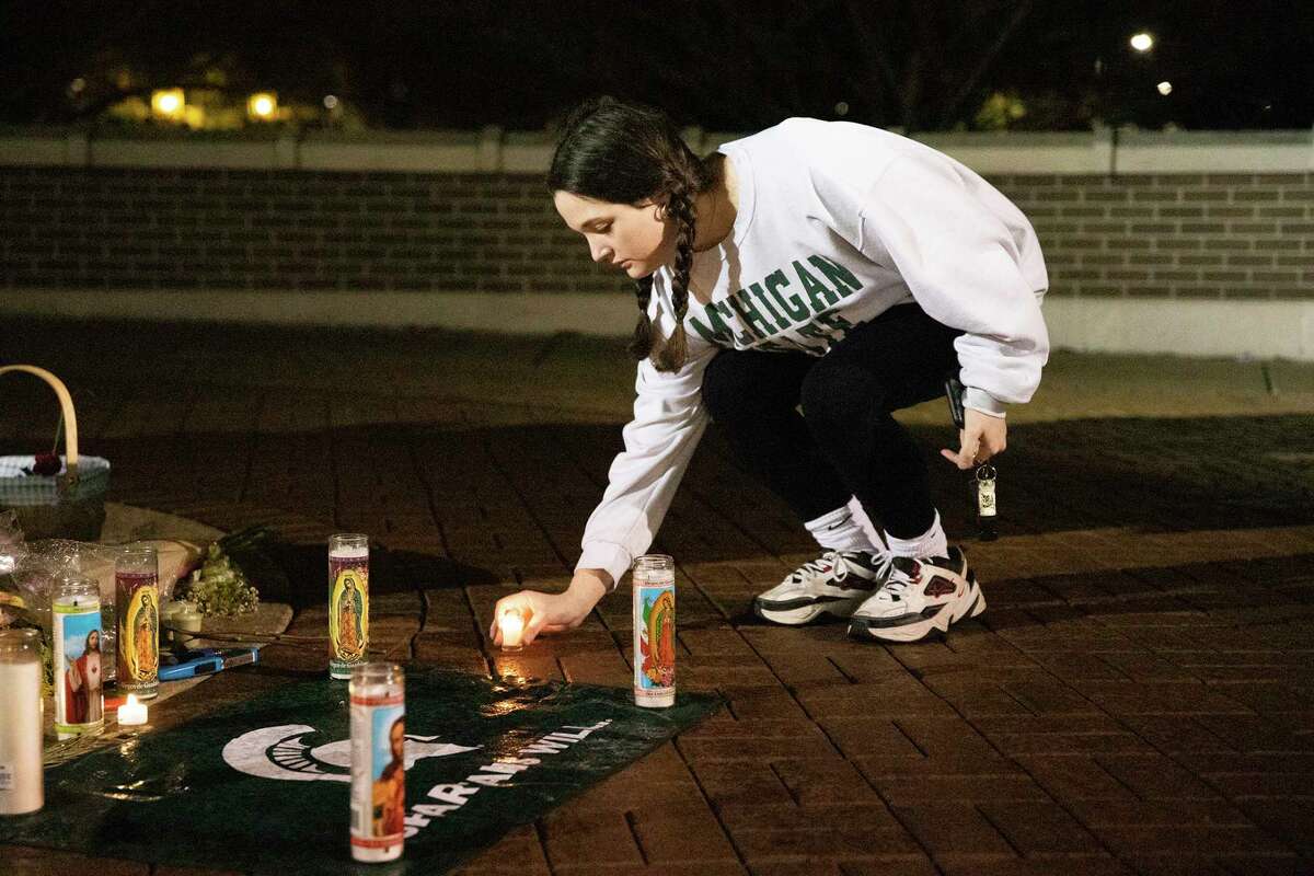 Maddie Kimball, a junior at Michigan State University from Spring Lake, Mich., lights a vigil candle at the Spartan Statue the night after a mass shooting on campus, in East Lansing, Tuesday, Feb. 14, 2023. (Brice Tucker/mlive.com/The Flint Journal via AP)
