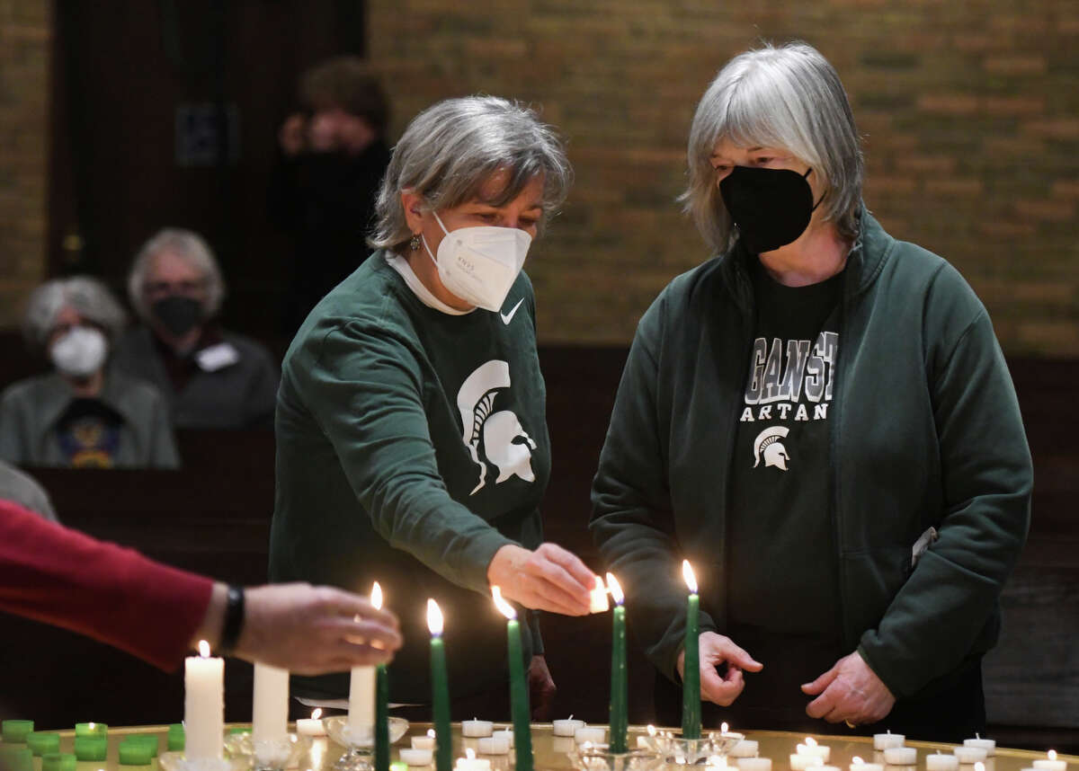 Colleen Johnson, left, and Ellen Ives light candles to honor Michigan State University students Brian Fraser, Alexandria Verner and Arielle Anderson, who died in a shooting on campus the night before, at Edgewood United Church in East Lansing, Mich., Tuesday, Feb. 14, 2023. (Matthew Dae Smith/Lansing State Journal via AP)