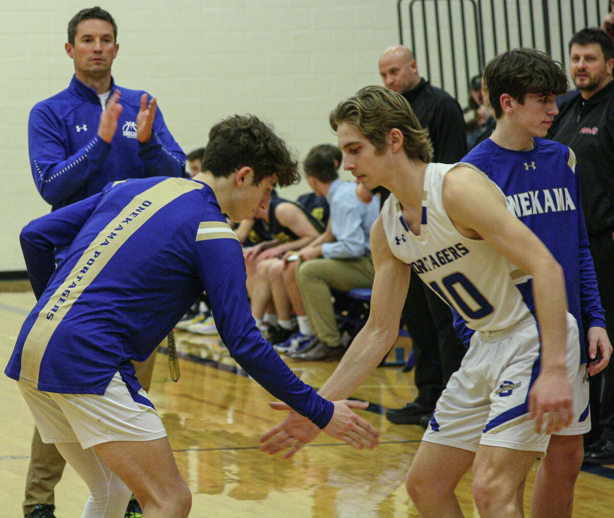 Onekama freshman Tyler Hart (left) goes through his pregame handshake with senior Sawyer Christensen (10) before a game against Manistee on Feb. 15, 2023 at Onekama Consolidated Schools. 