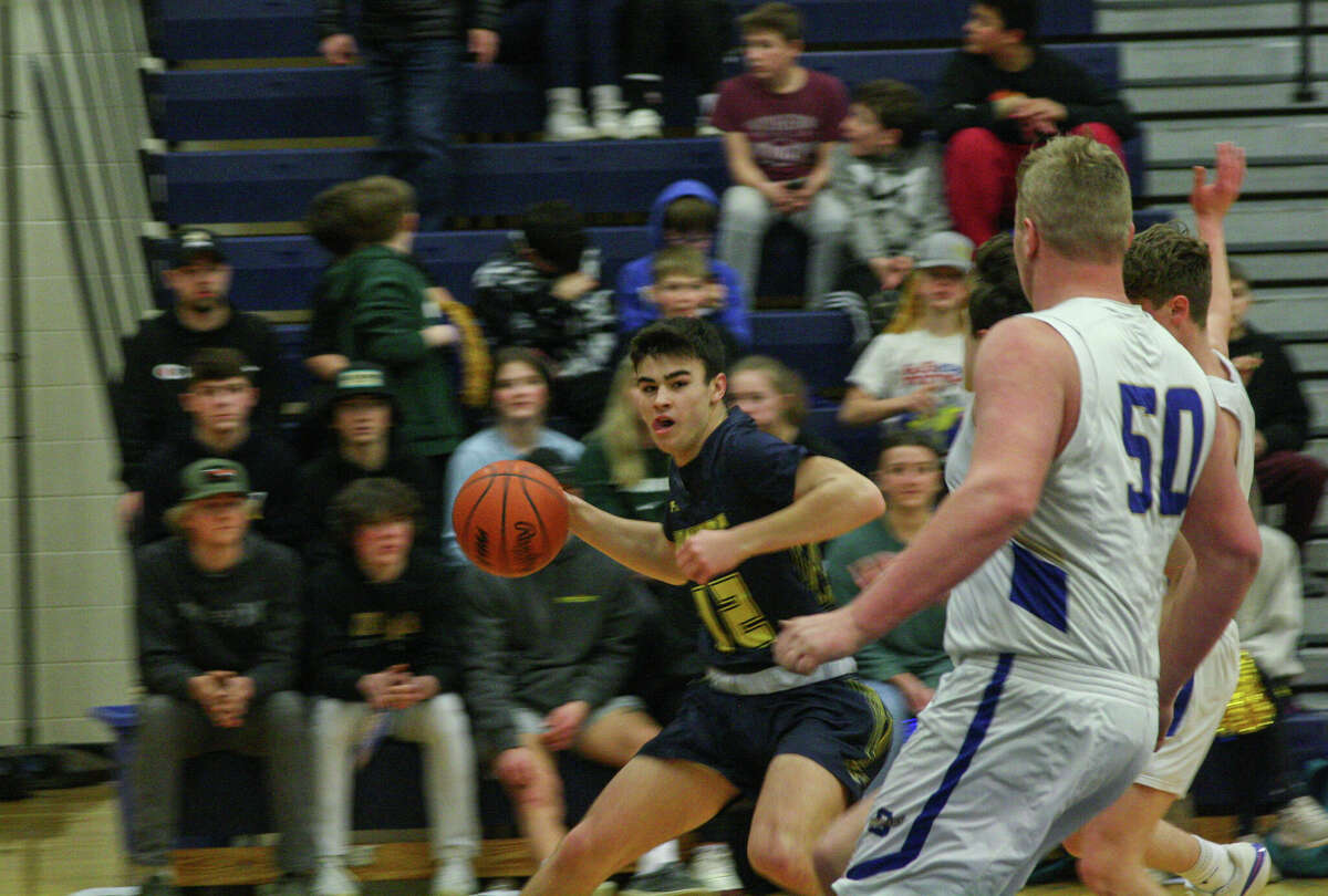 Manistee's Jacob Scharp (12) attempts to launch a pass past Onekama senior Adam Domres (50) on Feb. 15, 2023 at Onekama Consolidated Schools. 
