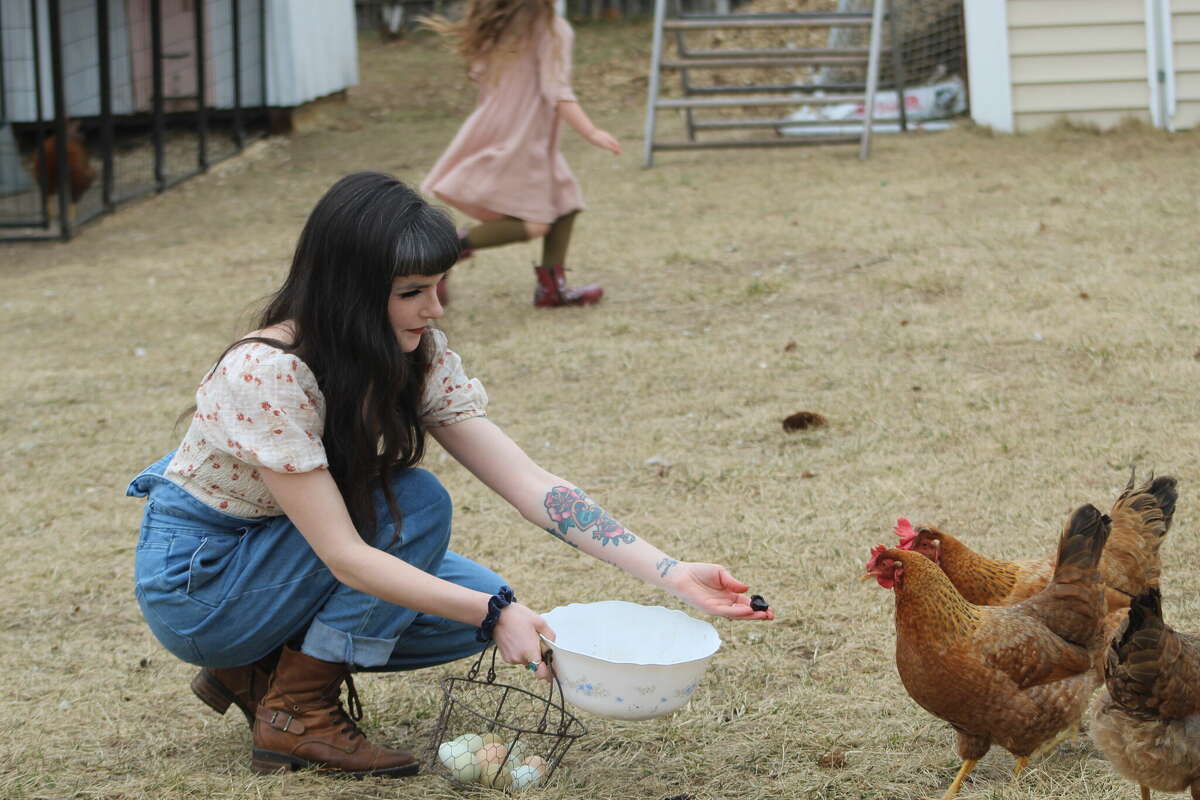 Heather Nicholson of Windsor Locks feeds her chickens in her yard, which is at the center of a debate in town over a zoning ordinance requiring chicken coops to be at least 100 feet from neighboring properties.