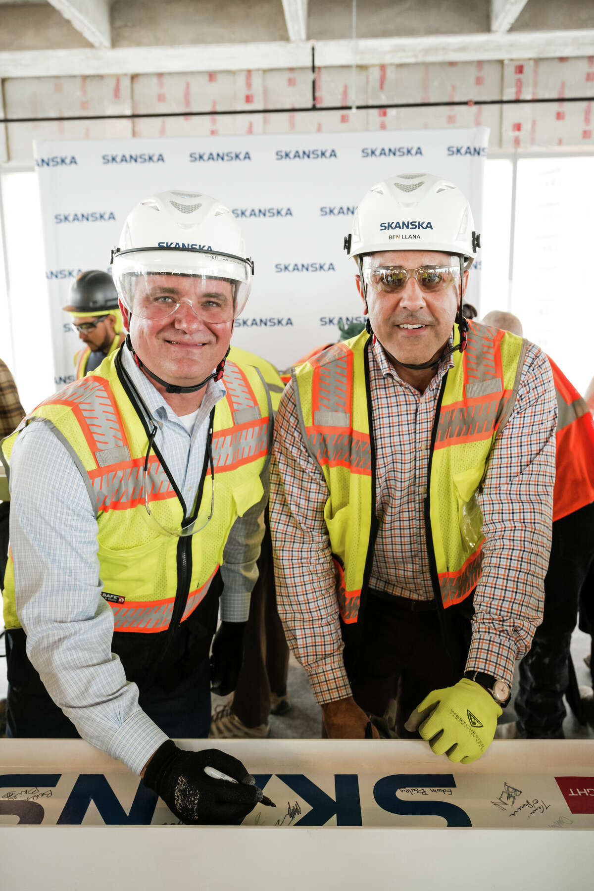 Skanska Executive Vice President Matthew Damborsky and Vice President Benjamin Llana signing a beam at a topping out ceremony for 1550 on the Green office tower in February 2023.