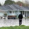 2023年1月16日，周一，一名路人走过加利福尼亚州沃森维尔市被洪水淹没的拉肯大道。加州遭受了一系列大气河流和巨大的海洋膨胀的袭击，造成了地区洪水和破坏。
