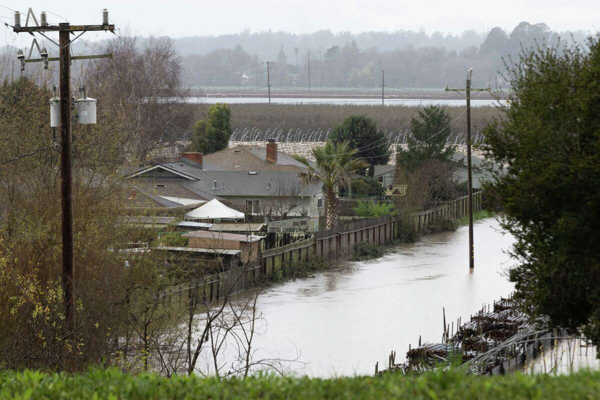 1月，在沃森维尔的拉肯大道上，一片被洪水淹没的农田紧邻着房屋。加州遭受了一系列大气河流和巨大的海洋膨胀的袭击，造成了区域洪水和破坏。