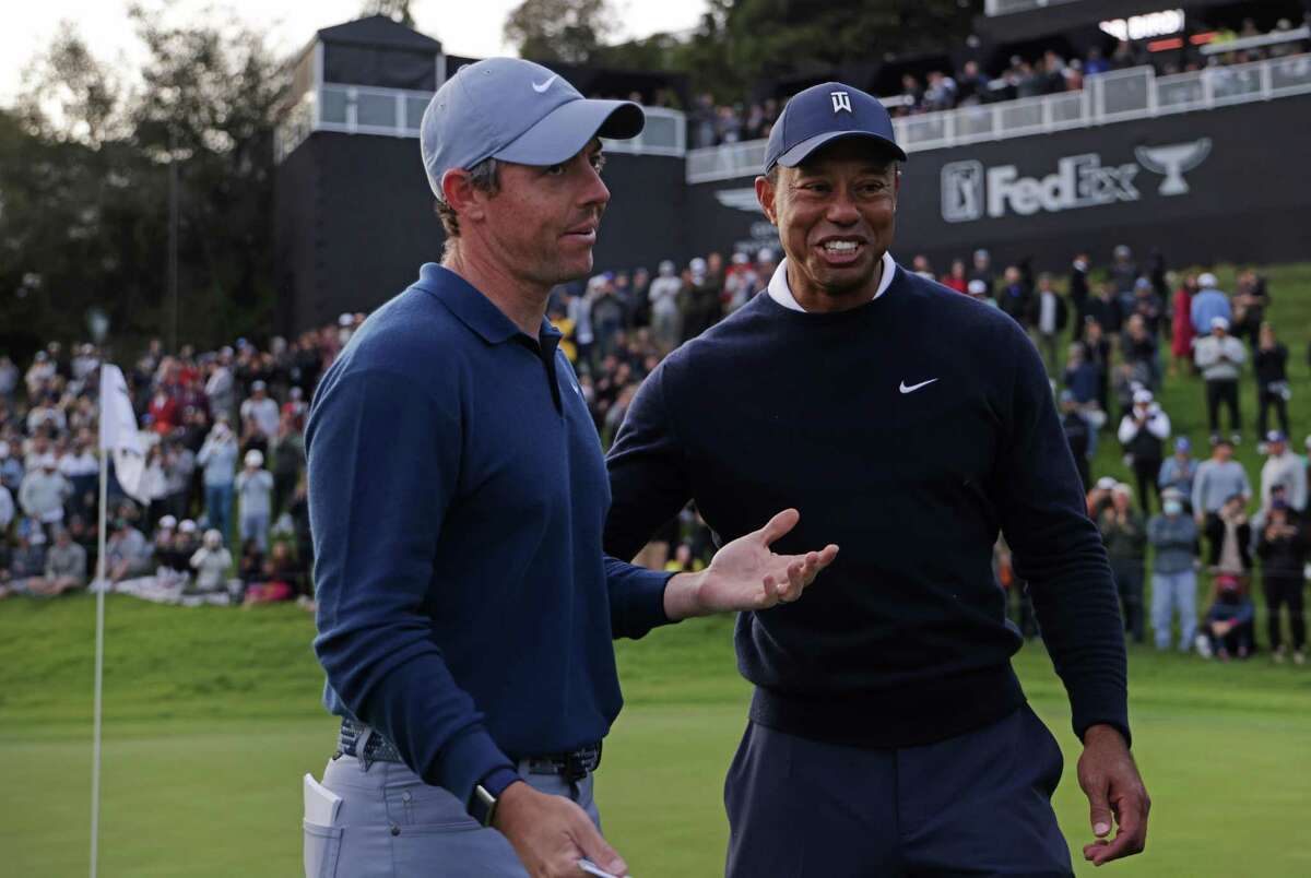 PACIFIC PALISADES, CALIFORNIA - FEBRUARY 16: Rory McIlroy of Northern Ireland (L) and Tiger Woods of the United States meet on the 18th green during the first round of the The Genesis Invitational at Riviera Country Club on February 16, 2023 in Pacific Palisades, California. (Photo by Harry How/Getty Images)