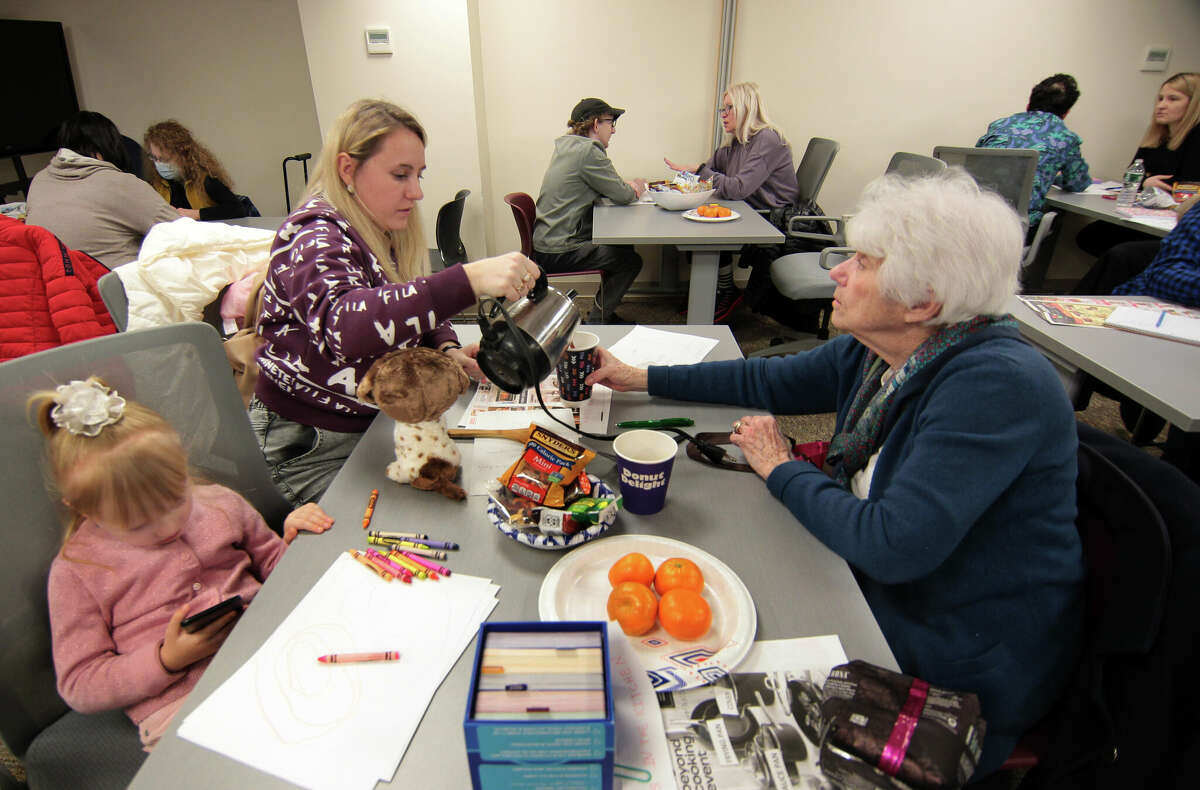 Ukrainian refugee Iryna Vanzhura, left, pours a cup of coffee as she learns English with the help of volunteer Muriel Ashley during a bi-weekly coffee hour held at the nonprofit group Jewish Family Service of Fairfield County in Stamford, Conn., on Wednesday February 15, 2023. Since July, the nonprofit's English Cafe program has been building a community for folks whose lives are completely in flux.