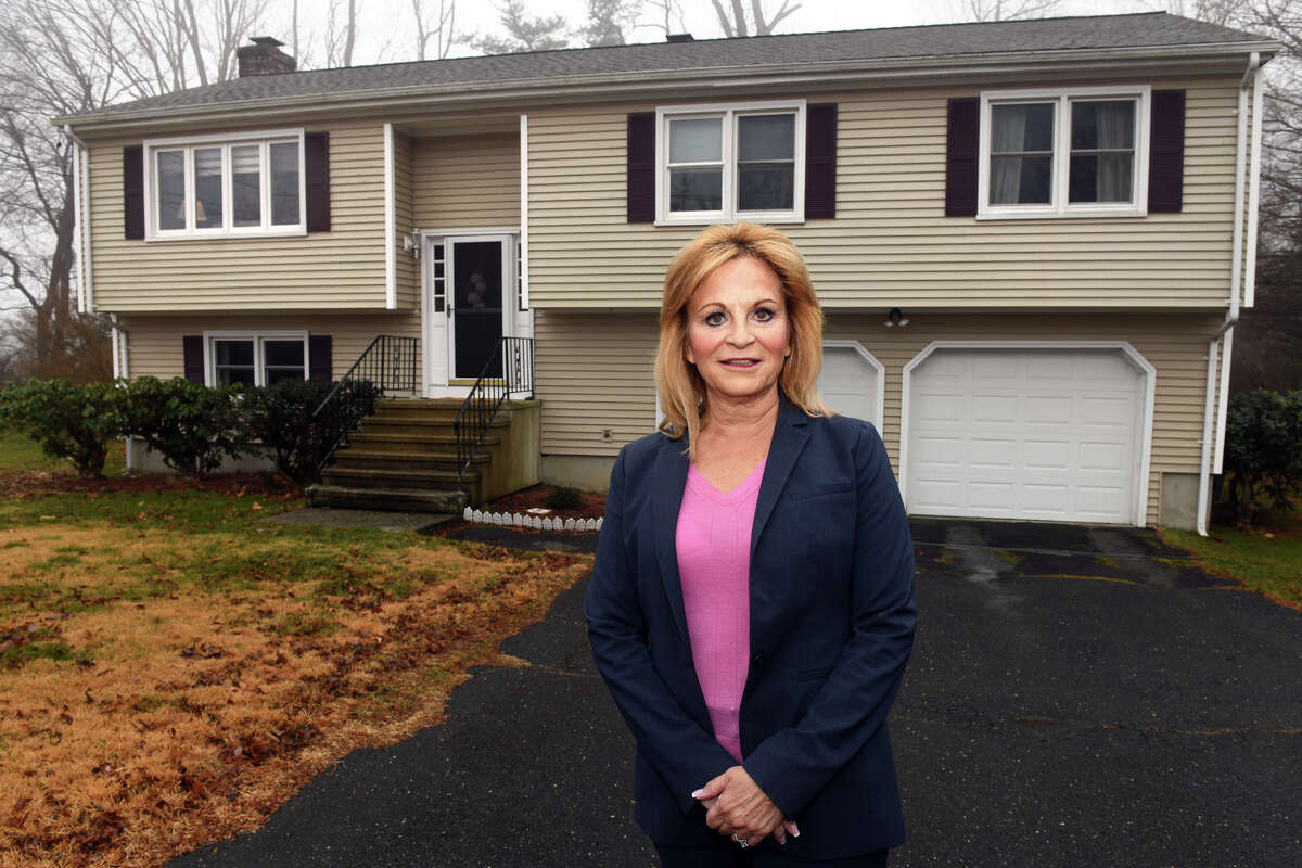 Real estate agent Stephanie Ellison poses in front of a home that will soon be put on the market in Milford, Conn. Feb. 17, 2023.