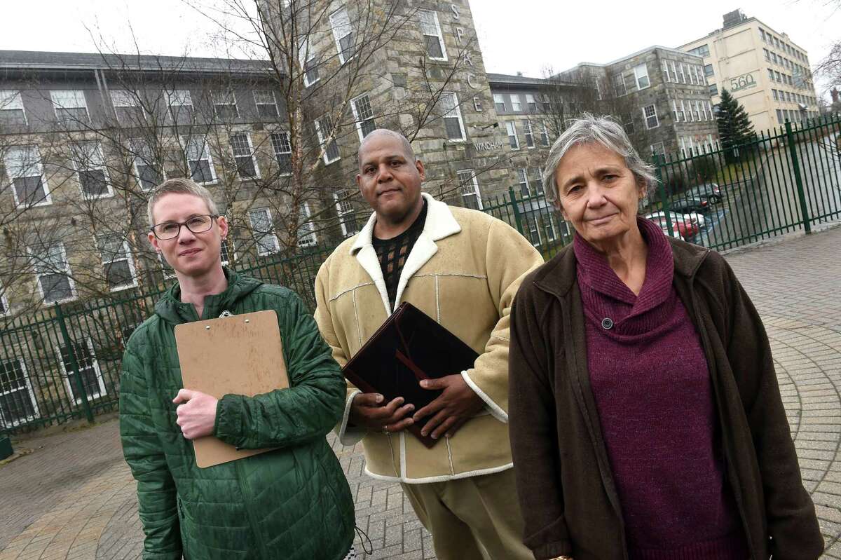 From left, Ara Wilnas, Jay Osborne and Marie Anne Beauchesne are photographed in front of the Artspace Windham apartments in Willimantic on February 17, 2023. The three are organizing the Windham Mills Tenant Union. In the background at right are the 560 on Main apartments.