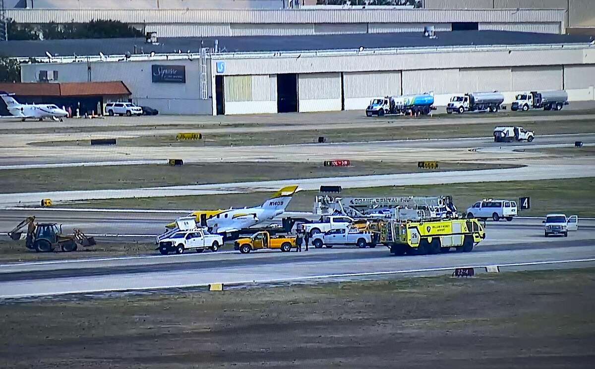 Maintenance vehicles work on a grassy safety area near a Hobby Airport runway intersection after a small plane wreck snarled air traffic at the travel hub on Friday.