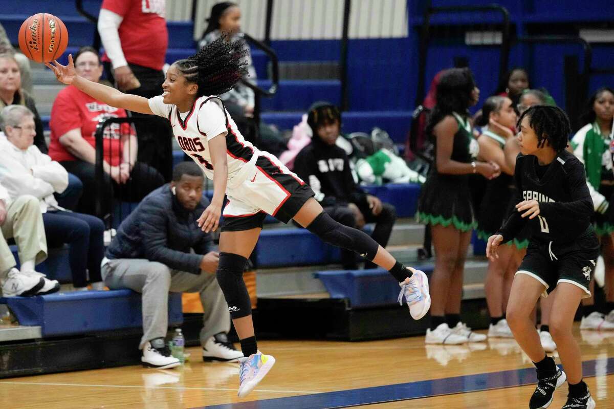 Langham Creek guard Aniyah Sanford, left, leaps for a loose ball as Spring guard Lanicea Thomas watches during the second half of a Region III-6A area high school basketball playoff game, Friday, Feb. 17, 2023, in Houston.