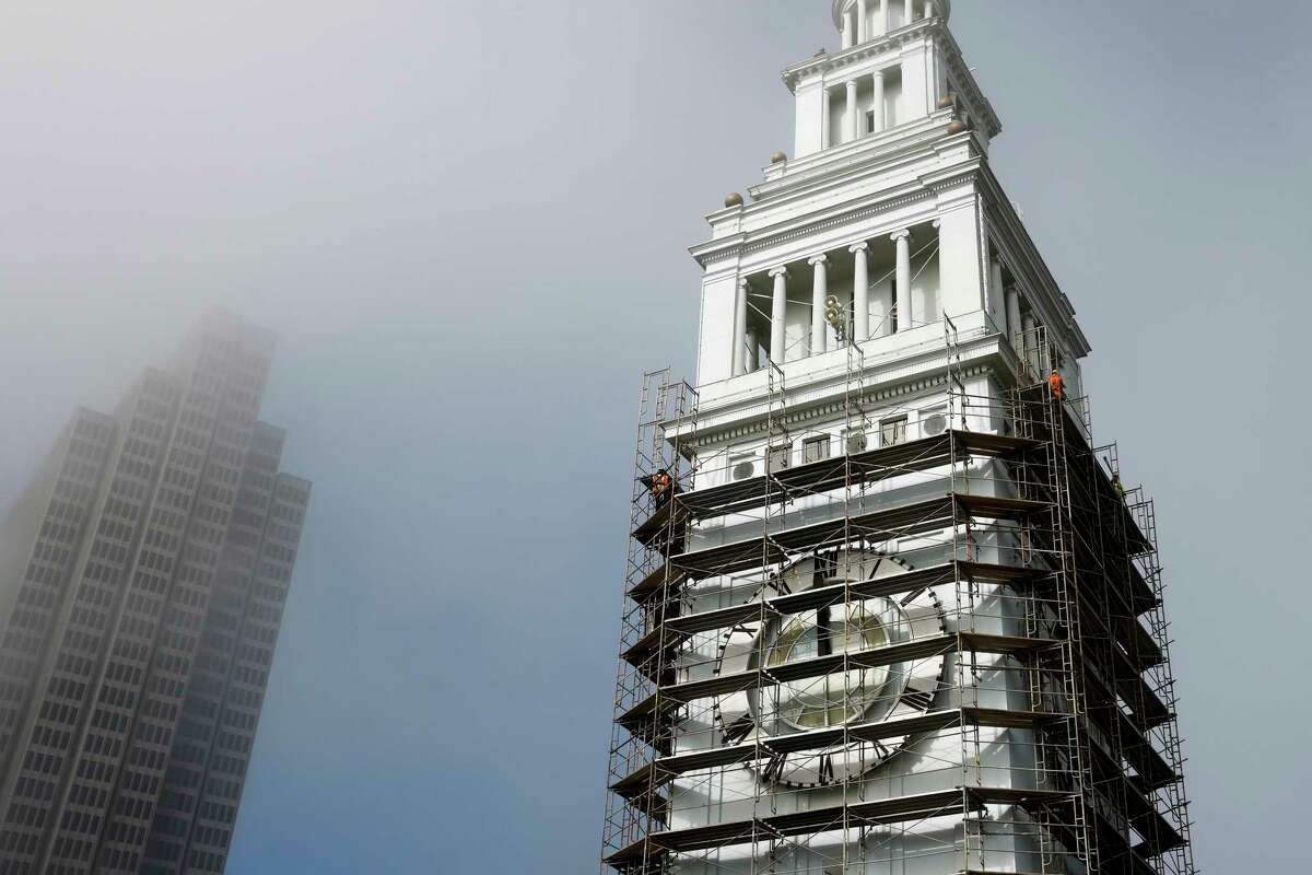 Crews walk across scaffolding erected around the historic tower of San Francisco's Ferry Building as part of a restoration project.