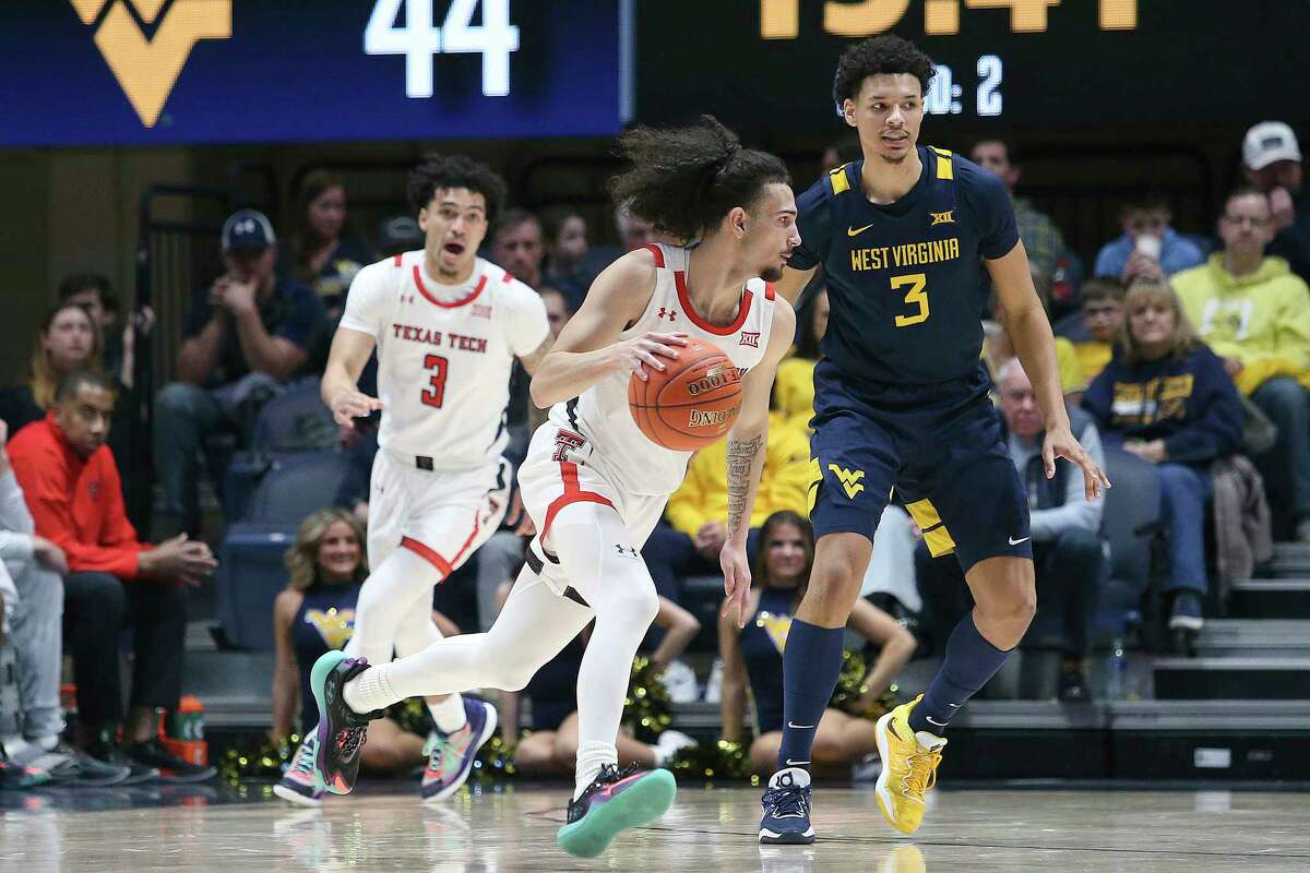 Texas Tech guard Pop Isaacs, left, dribbles as West Virginia forward Tre Mitchell (3) defends during the second half of an NCAA college basketball game on Saturday, Feb. 18, 2023, in Morgantown, W.Va.