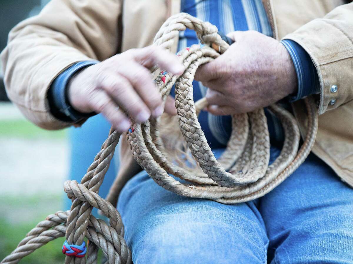 Mutt Neuman demonstrates how to wrap a rope at his Bar-n-Bar Rodeo Arena in Dayton, Texas on Thursday, Feb. 16, 2023. Neuman’s been training youth to go to the rodeo for years, as everything in his small town change around him, strip malls rising in place of cow pastures.