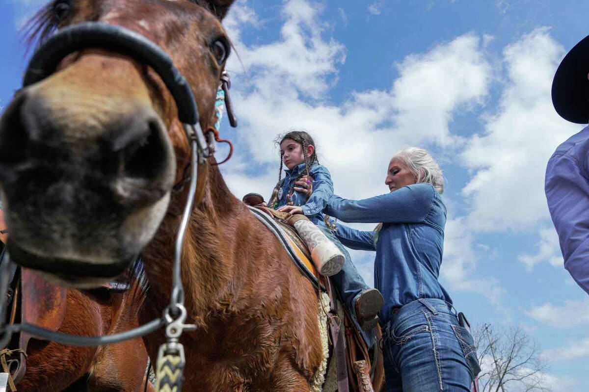 Bernadette Gonzales helps her daughter, Autumn, 7, mount her horse Reno as they prepare to ride out with The Sam Houston Trail Riders on their way to Rodeo on Tuesday, Feb. 21, 2023 at in Houston, TX.