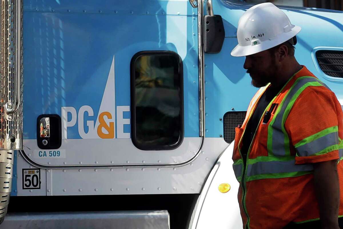 2019年，一名太平洋天然气和电力公司的工人走在旧金山的一辆卡车前。PG&E表示，周二的强风导致超过7.1万名客户断电。