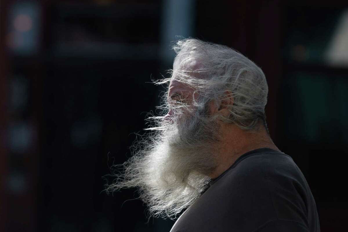 2023年2月21日，星期二，加州旧金山，一名行人顶着大风走在第五街，用头发和胡子遮住脸。