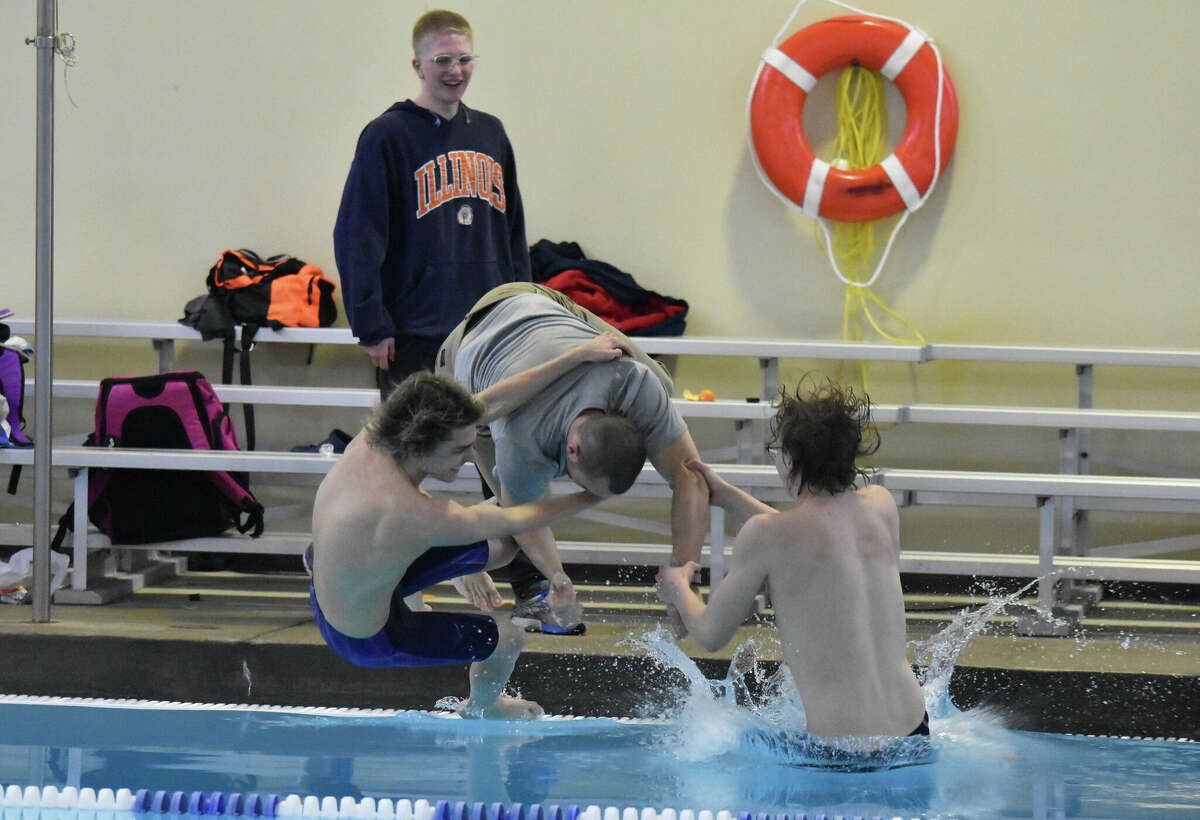Edwardsville swimmers celebrate winning the program's fifth consecutive sectional title on Saturday by pulling coach Christian Rhoten into the pool of the Chuck Fruit Aquatic Center.