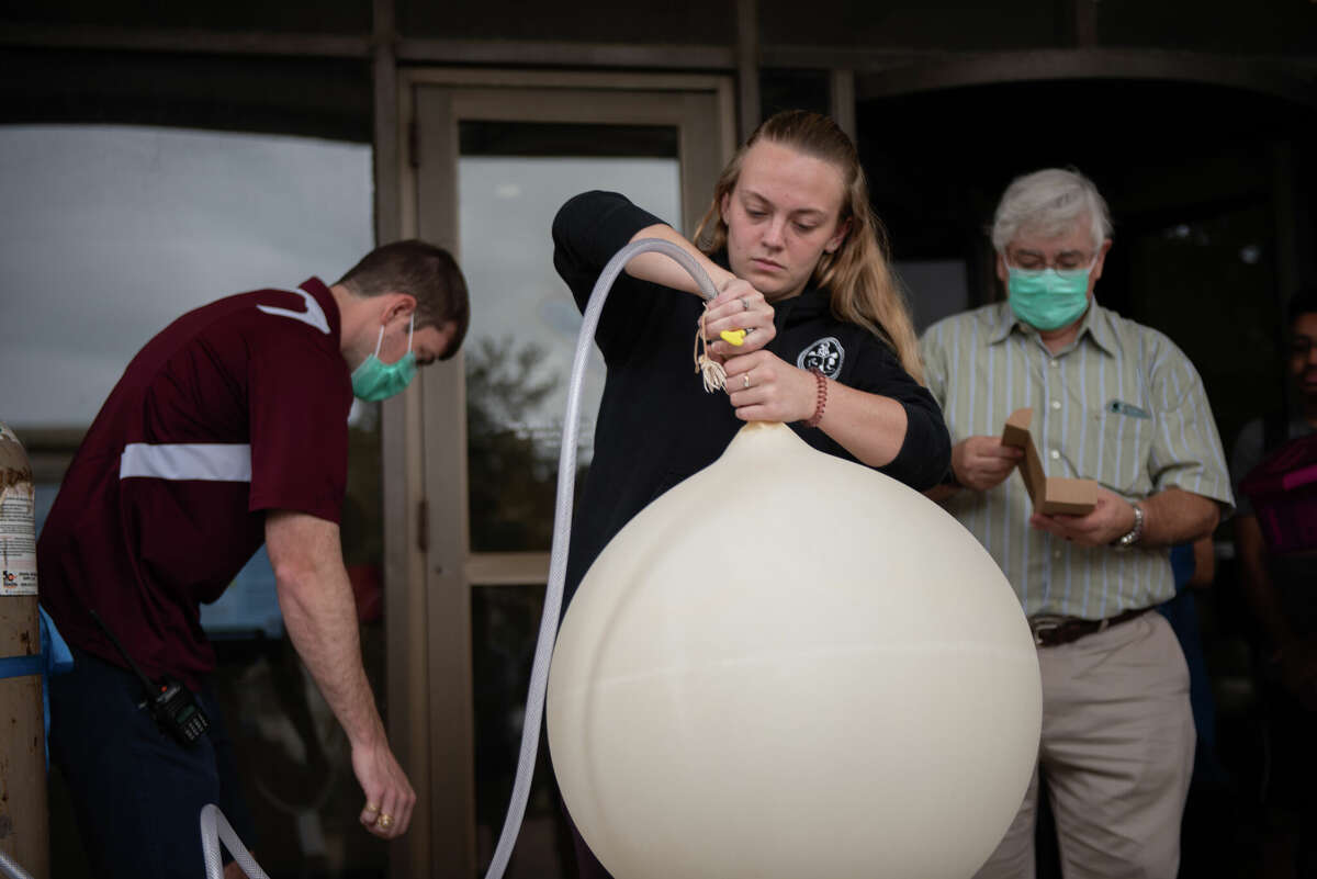 Dr. Erik Nielsen, Madelyn Hess, and Dr. Don Conlee fill a weather balloon with helium while preparing for a balloon launch on Oct. 24, 2022 as a part of the Texas A&M Student Operational Upper-Air Program. 