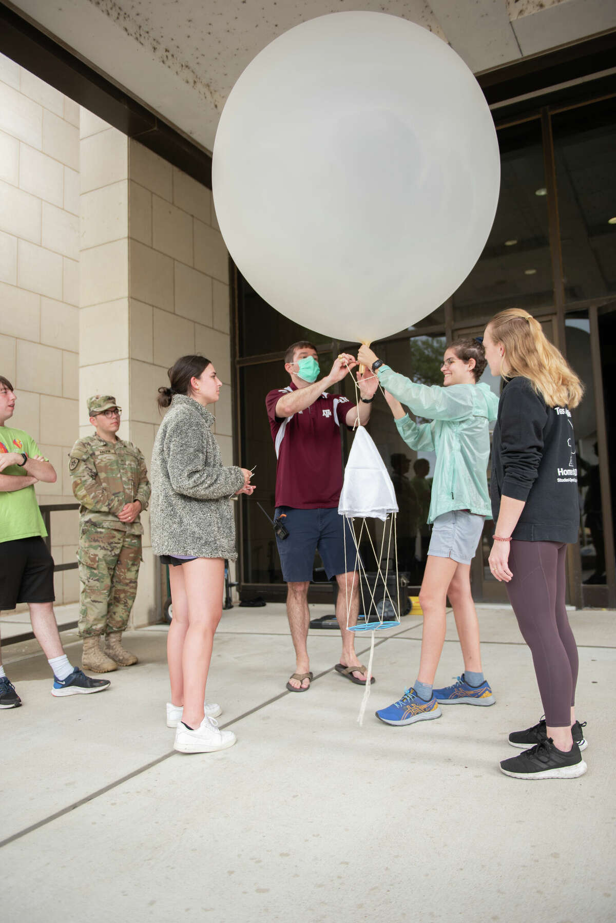 Brian Neuville, Jonathan Halpin, Clara Holloway, Dr. Erik Nielsen, Sierra Hill, and Madelyn Hess attach the radiosonde parachute to a weather balloon while preparing for a balloon launch on Oct. 24, 2022 as a part of the Texas A&M Student Operational Upper-Air Program.