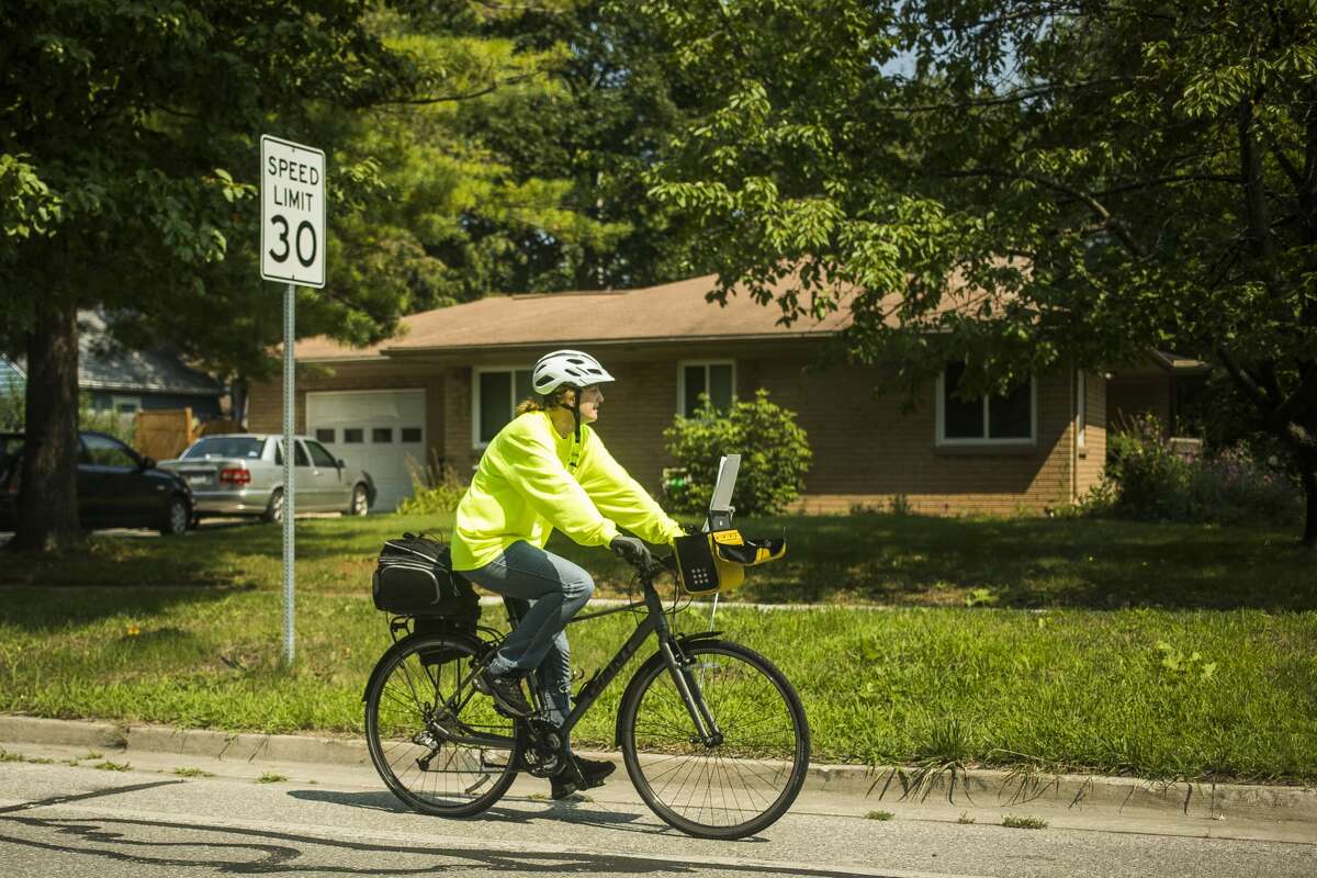 Midland County Mosquito Control employee Jenni Lewis of Coleman rides from one water catch basin to the next, dropping mosquito growth regulator pellets into each one, Tuesday, July 20, 2021 in Midland.