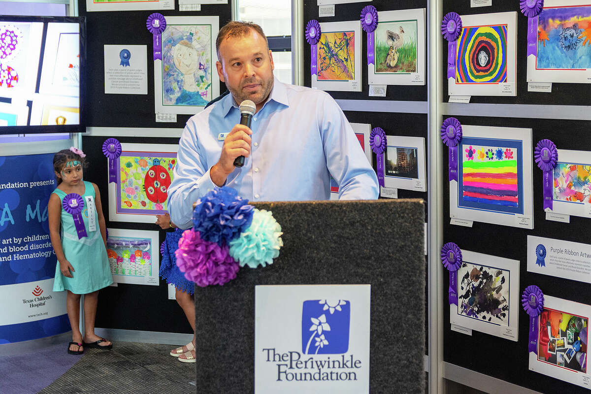 Doug Suggitt with Periwinkle Foundation chats with supporters surrounded by numerous art pieces with a young artist looking on. One of the expansions under Suggitt's leadership has been the inclusion of the arts offered to young patients.