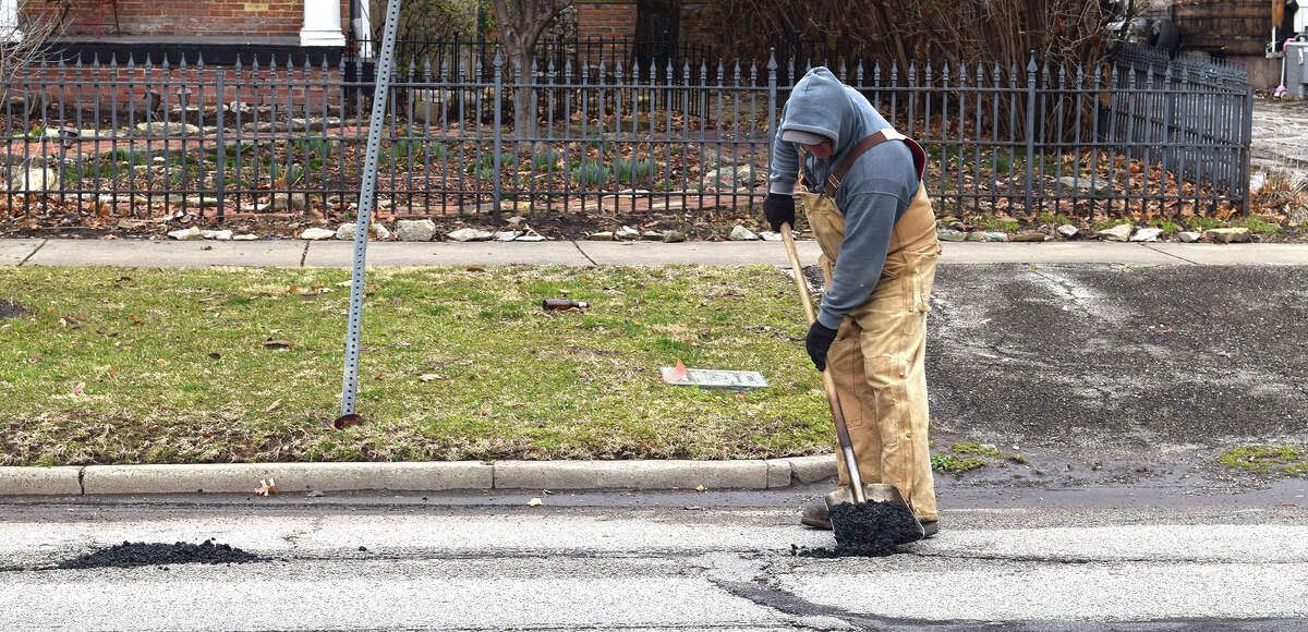 Jacksonville Street Department worker Rich Hymes uses asphalt to patch a pothole along West College Avenue.