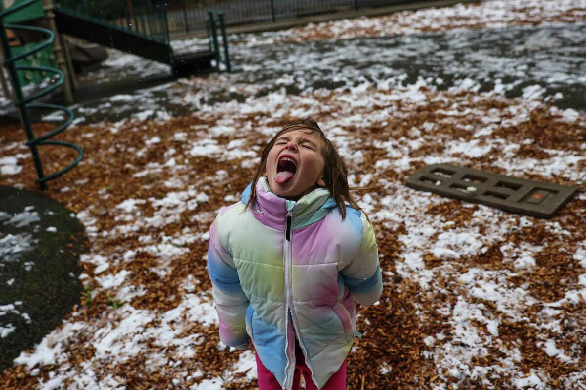 Giana Yearry, 7, sticks out her tongue to catch snow as she plays on the playground off of Bayview Drive in Los Gatos, Calif., on Thursday, Feb. 23, 2023. It was Giana’s first time seeing snow.
