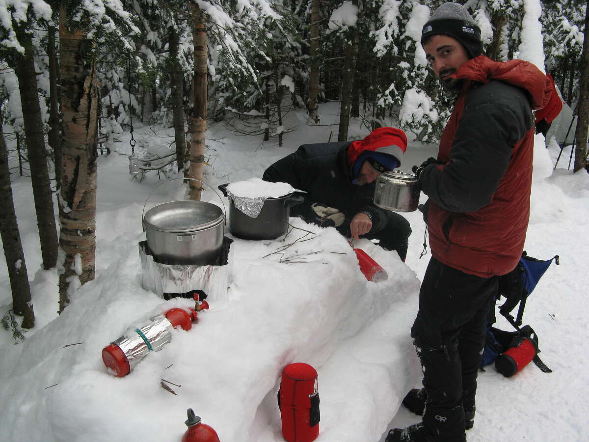 Winter Mountaineering School participants prepare a meal at their outdoor kitchen.