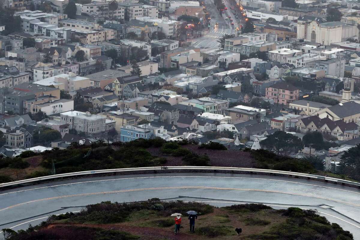 游客们在周四的雨中走在旧金山的双峰上。