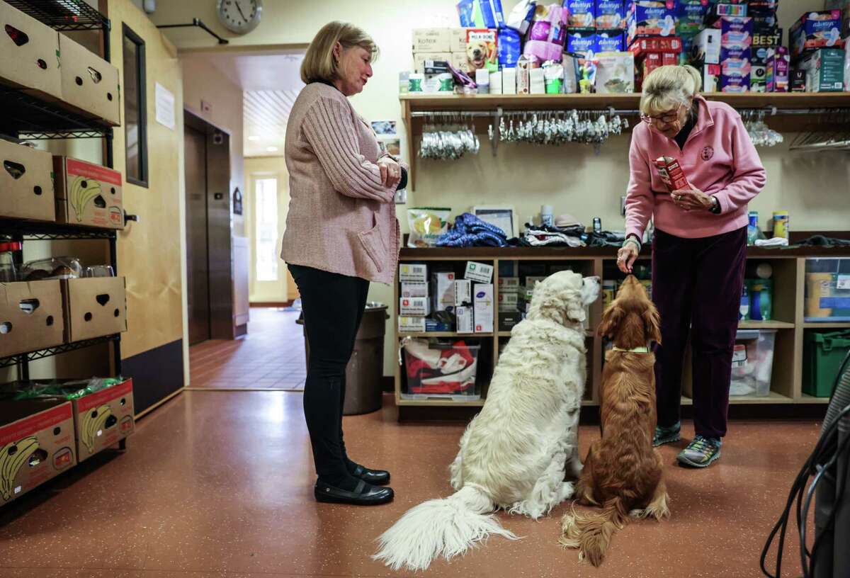 Sister Christina Heltsley (left) chats with Barbara Thurston, who took a break from organizing clothing to give out dog treats at the St. Francis Center in Redwood City.