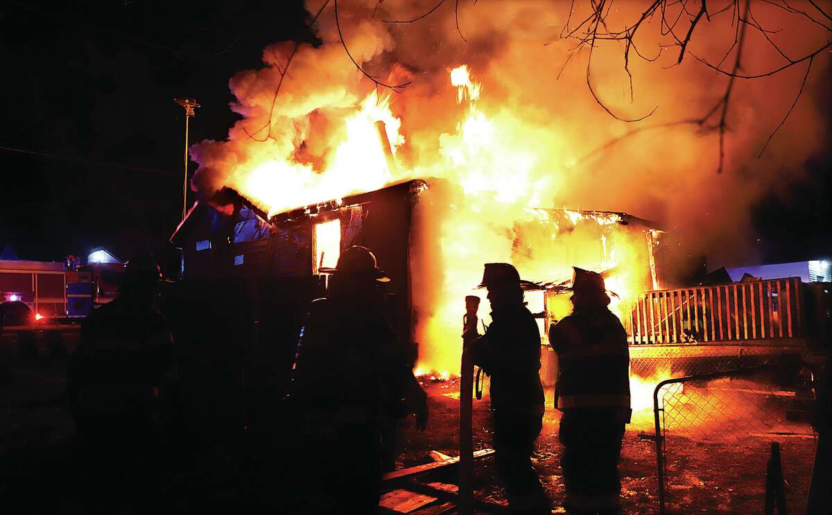 Firefighters are silhouetted by the flames engulfing a house early Friday morning in the first block of Circle Drive in Cottage Hills. Four fire departments battled the flames for three hours. 