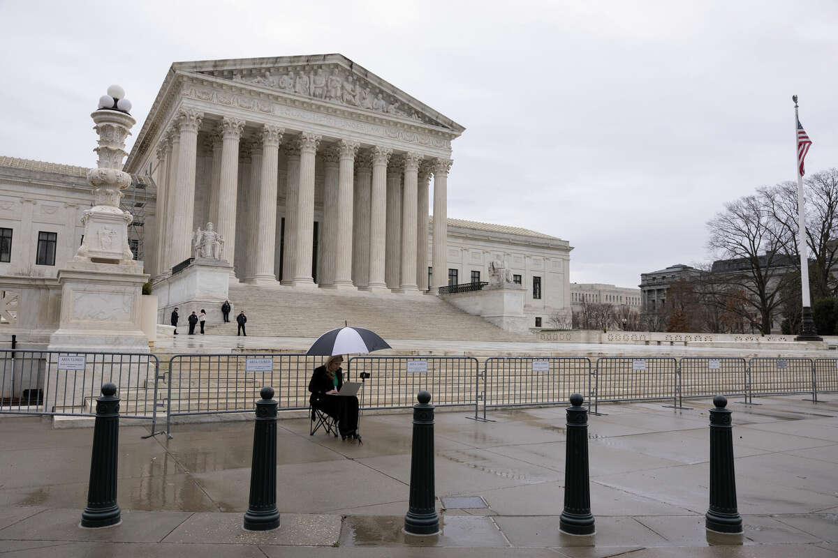 A woman works on her laptop outside of the U.S. Supreme Court on February 22, 2023 in Washington, DC. 
