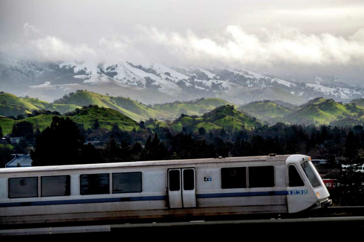 当一辆BART列车离开核桃溪站时，积雪覆盖了迪亚波罗山。