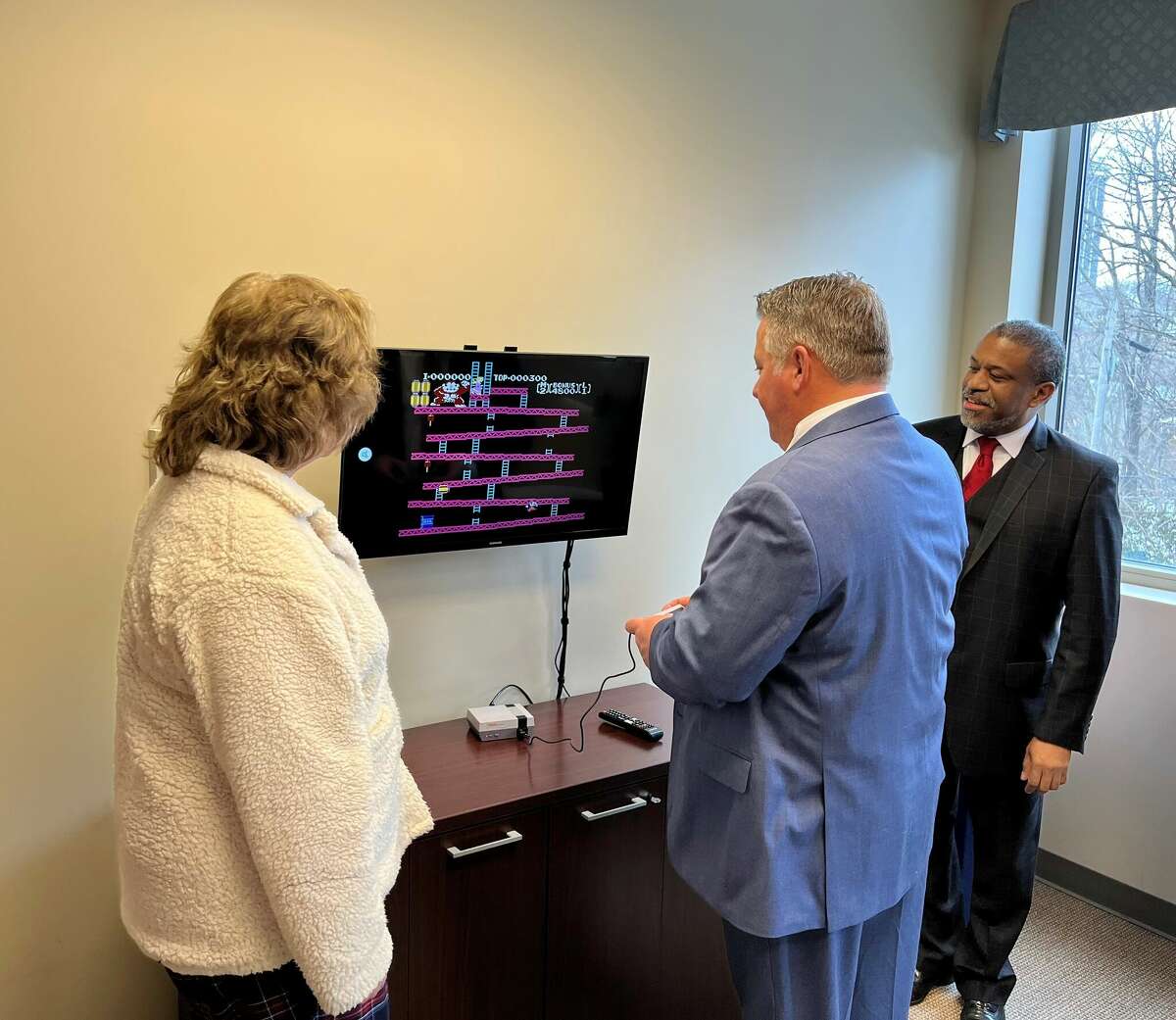 Albany County Executive Daniel McCoy, accompanied by Family Court Judge Richard Rivera and Albany County Department of Children, Youth and Families Moira Manning, tries his hand at the video game classic Donkey Kong at the ribbon-cutting of a special room for foster youth in Albany County Family Court on Friday, Feb. 24, 2023. The room is designed to ease the experience of Family Court for the youths.