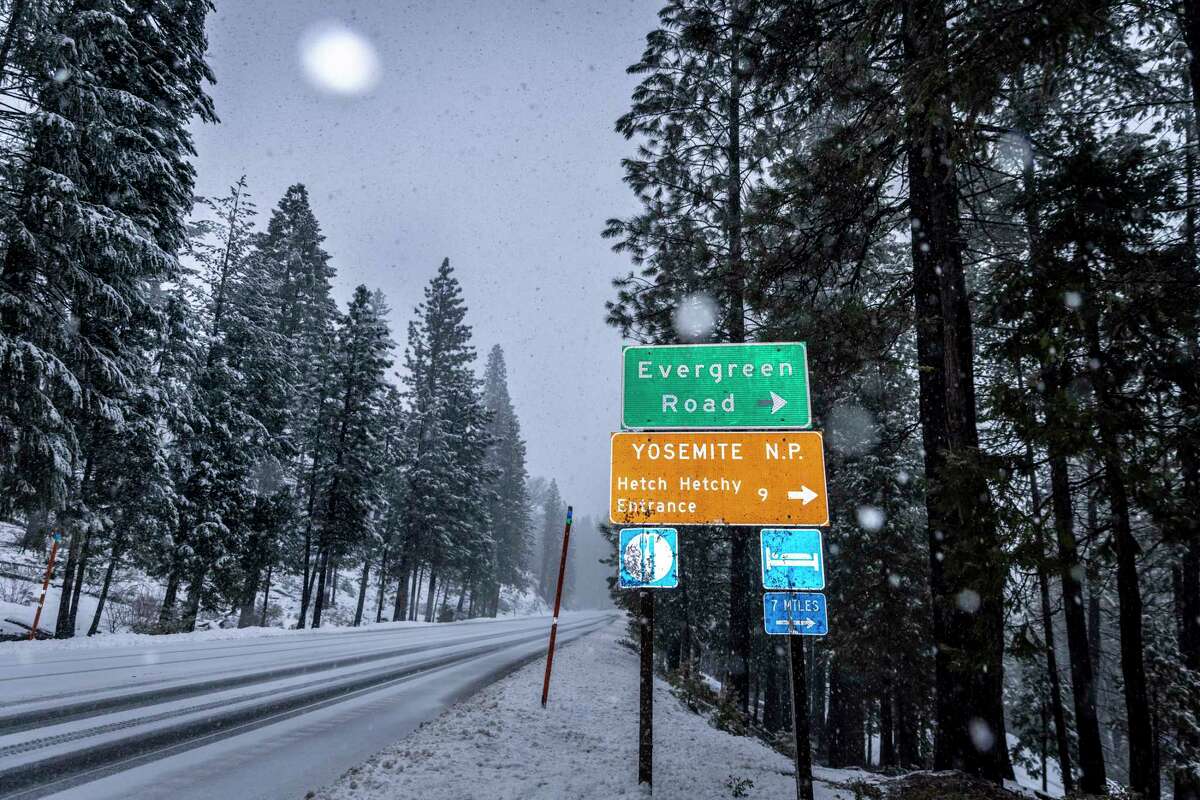 Snow falls on Highway 120 near the sign to Hetch Hetchy Reservoir outside Yosemite National Park on Feb. 5.  Storms have forced the park to close roads to the public until Wednesday.