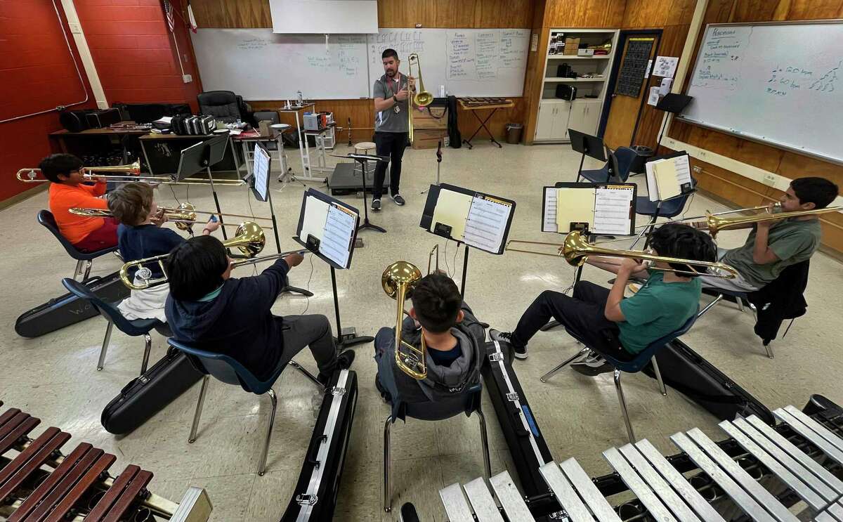 Despite wearing hearing aids because of hearing loss, Adam Chitta is assistant band director at Wood Middle School. He works with trombone students on Thursday, Feb. 16.