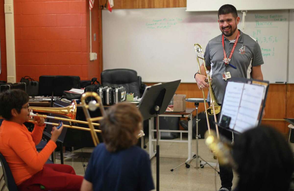 Despite wearing hearing aids because of hearing loss, Adam Chitta is assistant band director at Wood Middle School. He works with trombone students on Thursday, Feb. 16.