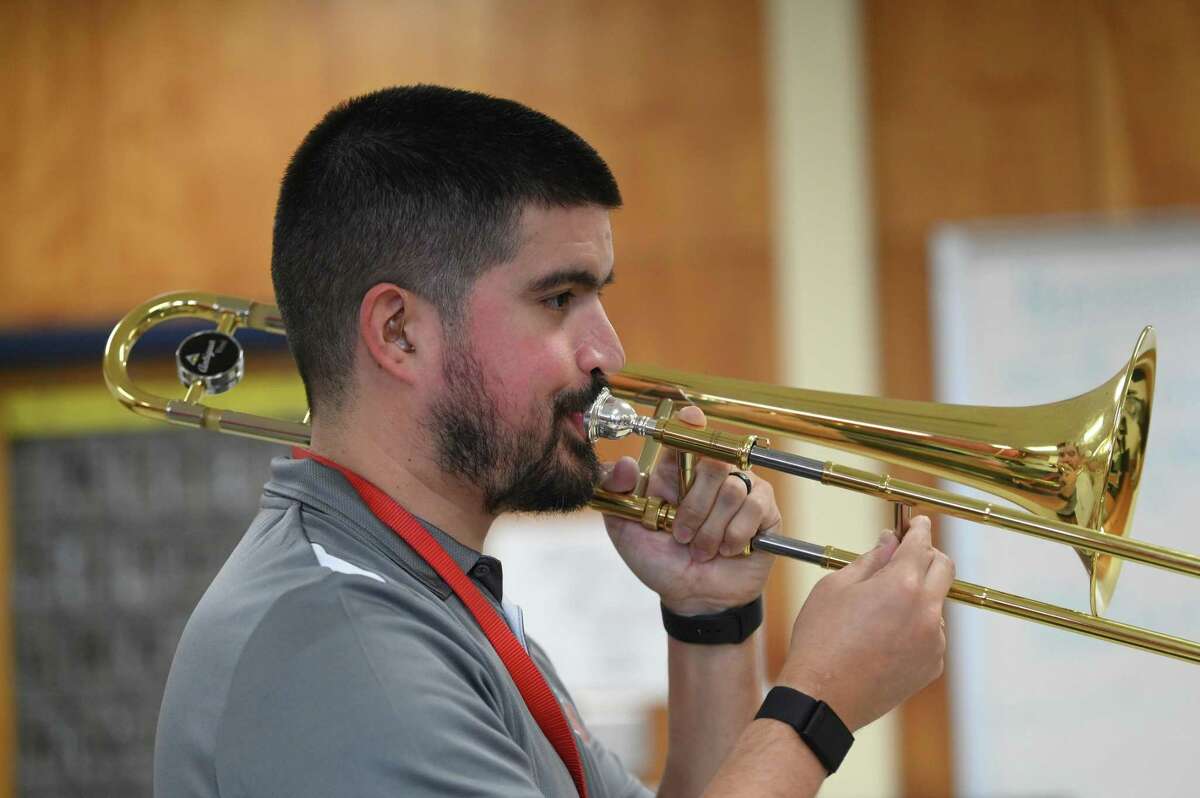 Despite wearing hearing aids because of hearing loss, Adam Chitta is assistant band director at Wood Middle School. He works with trombone students on Thursday, Feb. 16.