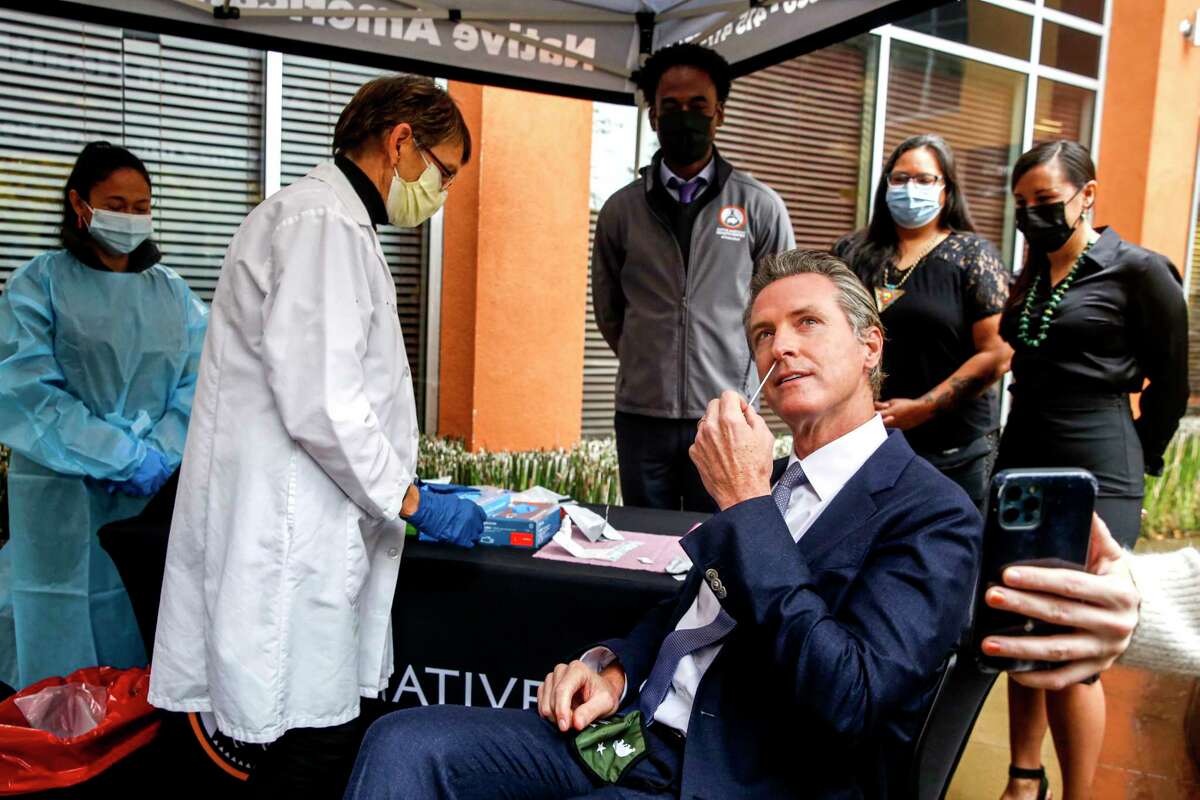 州长Gavin Newsom用药时快速测试之前宣布新国家行动保护加州日益COVID-19病例和新ο变体在新闻发布会上美国原住民健康中心在奥克兰,加州在周三,2021年12月22日。
