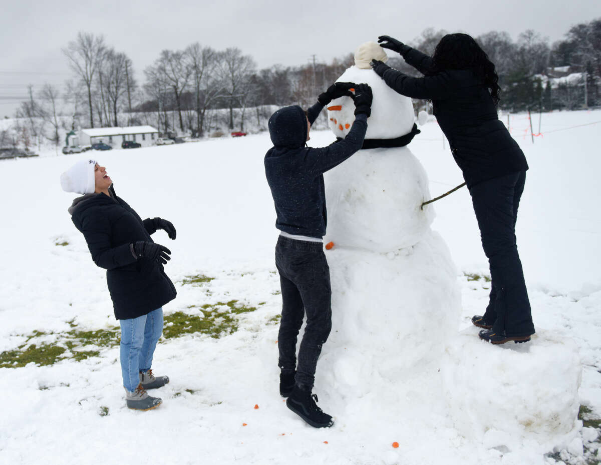 Stamford's Jennifer Lopez, left, Peter Flausino, center, and Camila Lopez put the finishing touches on their snowman, named Sam, at Binney Park in Old Greenwich, Conn. Tuesday, Feb. 28, 2023. The area received its first measurable snow accumulation of the year, albeit just a few inches, from a storm Monday night through Tuesday morning.