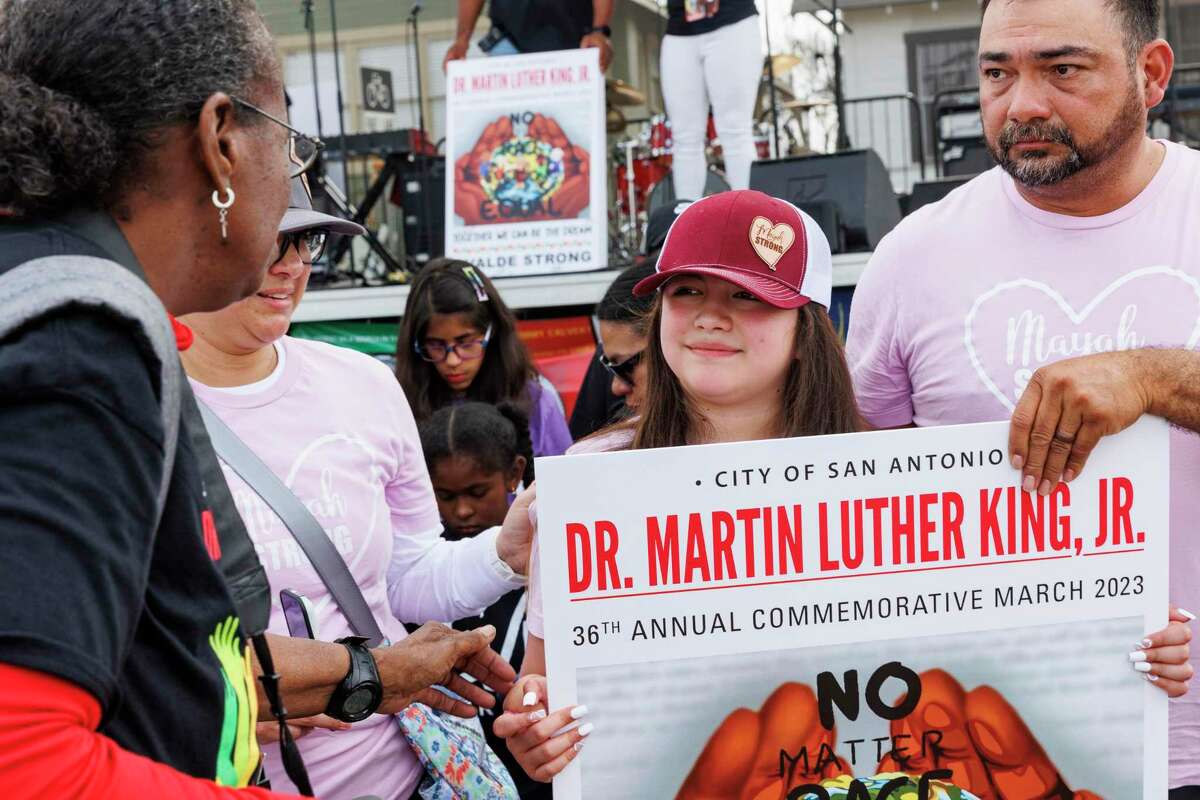 Mayah Zamora, a survivor of the Robb Elementary massacre, center, is applauded by people attending the 36th annual Martin Luther King Jr. March and festives in San Antonio, Texas, Monday, Jan. 16, 2023. Her parents Christina and Reuben and 12-year-old brother Zachary attended the march with her.
