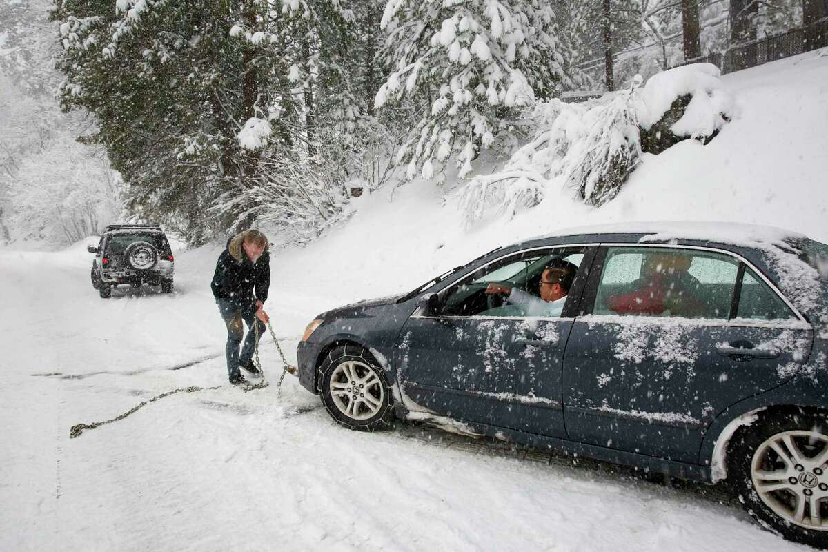 Kevin Spier (left) of Sacramento helps Ken Ngo (driving) and Hailey Nguyen, both of San Jose, get their car unstuck along westbound Highway 50 near Kyburz ( El Dorado County) on Tuesday..
