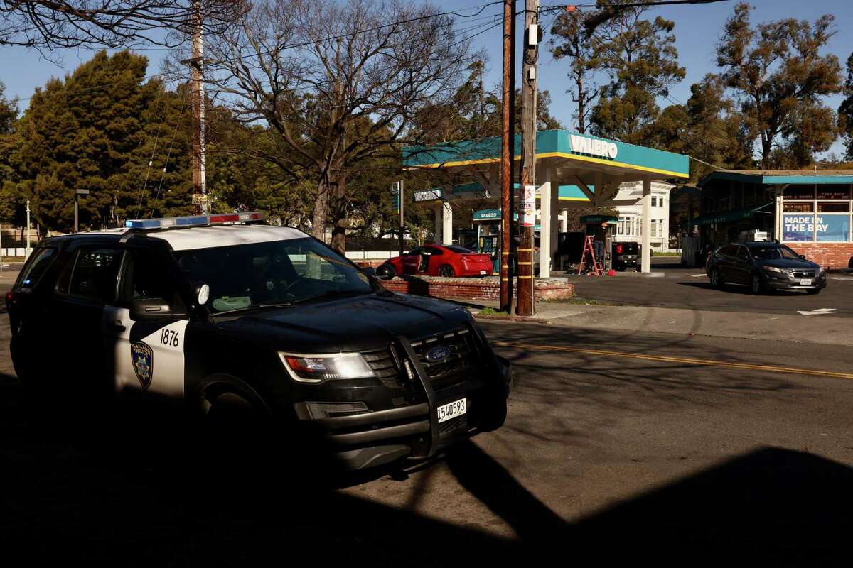 An Oakland police vehicle is parked across the street from a Valero gas station where a mass shooting left one person dead. A San Leandro man has been charged with nine felony counts including murder. 