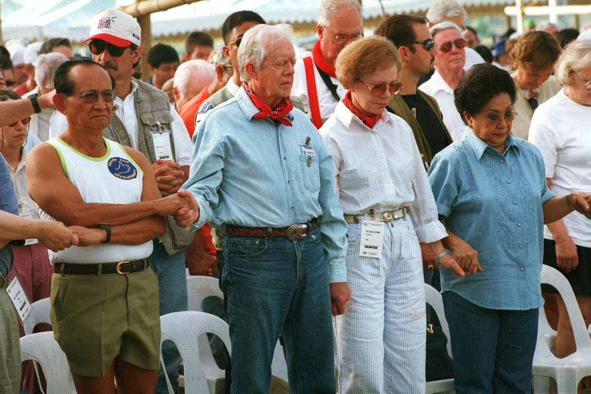 Former U.S. President Jimmy Carter, second from left, joins hands with former Philippine President Fidel Ramos, left, former U.S. first lady Rosalynn Carter, cecond from right, and former Philippine first lady Amelita Ramos as they pray Monday, March 22, 1999 in Maragondon, 64 kilometers (40 miles) southwest of Manila, Philippines, before they and volunteers began the construction of low-cost homes for poor Filipinos. The volunteers, along with slum dwellers, plan to put up a total of 293 single-story concrete houses in Maragondon and four other sites nationwide in a week's time, said Millard Fuller, founder of the non-profit group Habitat for Humanity, which organized the project.(AP Photo/Pat Roque)